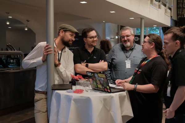 Attendees talking around a table with a laptop